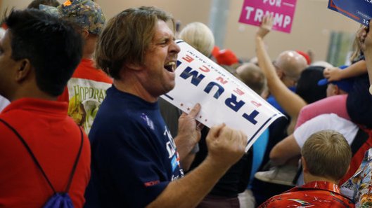 A man yells at the media as Republican presidential nominee Donald Trump speaks during a campaign event in Phoenix